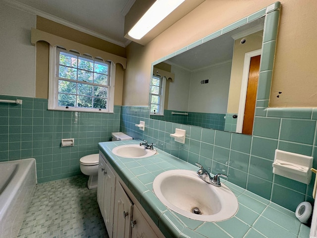 bathroom featuring a tub to relax in, toilet, vanity, tile walls, and ornamental molding