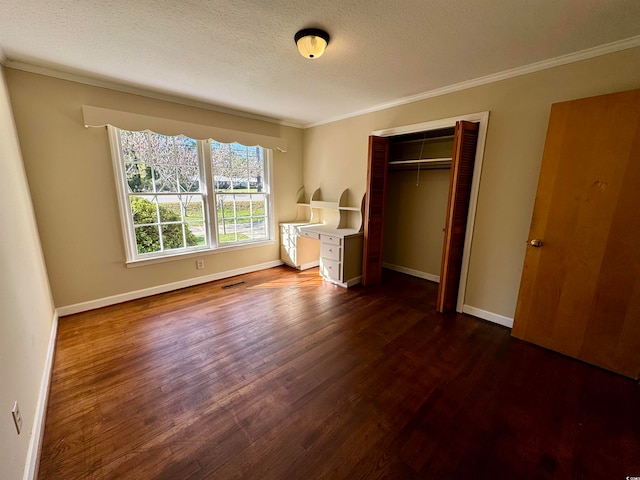 unfurnished bedroom with a closet, crown molding, dark hardwood / wood-style flooring, and a textured ceiling