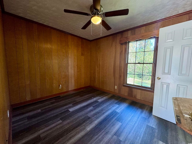 unfurnished room with a textured ceiling, dark hardwood / wood-style flooring, ceiling fan, and wooden walls