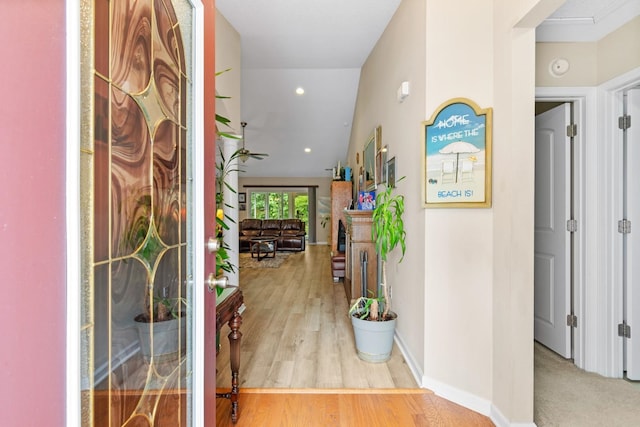 corridor with hardwood / wood-style floors and vaulted ceiling