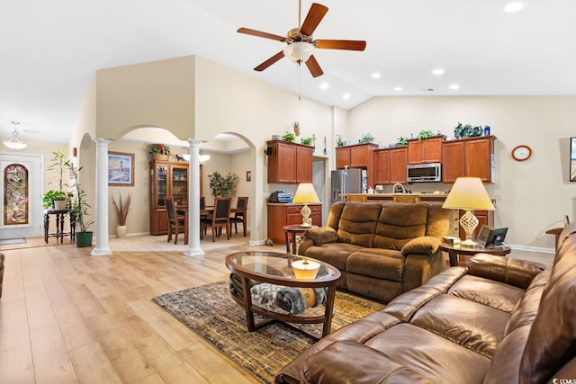 living room featuring ceiling fan, high vaulted ceiling, decorative columns, and light hardwood / wood-style flooring