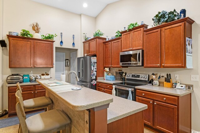 kitchen featuring a kitchen breakfast bar, vaulted ceiling, stainless steel appliances, sink, and a center island