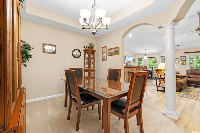 dining space featuring vaulted ceiling, ornate columns, ceiling fan with notable chandelier, and light wood-type flooring