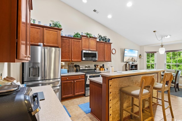 kitchen with a kitchen breakfast bar, hanging light fixtures, a center island, light tile patterned flooring, and appliances with stainless steel finishes