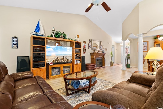 living room featuring decorative columns, light hardwood / wood-style flooring, high vaulted ceiling, and a healthy amount of sunlight