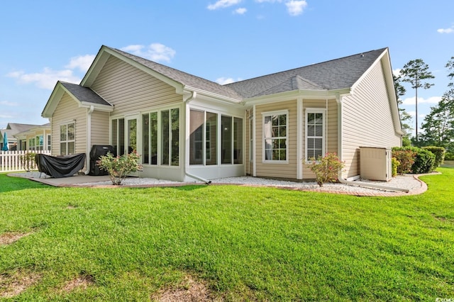 rear view of property featuring a patio, a yard, and a sunroom