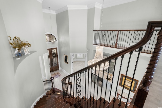 stairway with a notable chandelier and ornamental molding