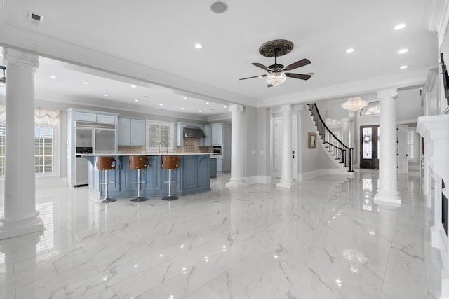 kitchen featuring a large island, a kitchen bar, wall chimney range hood, and ornamental molding