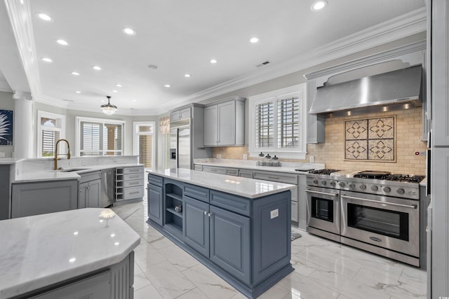 kitchen featuring a center island, high end appliances, backsplash, sink, and wall chimney exhaust hood