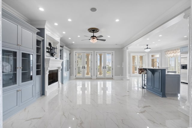 living room with ornate columns, ceiling fan, crown molding, and sink