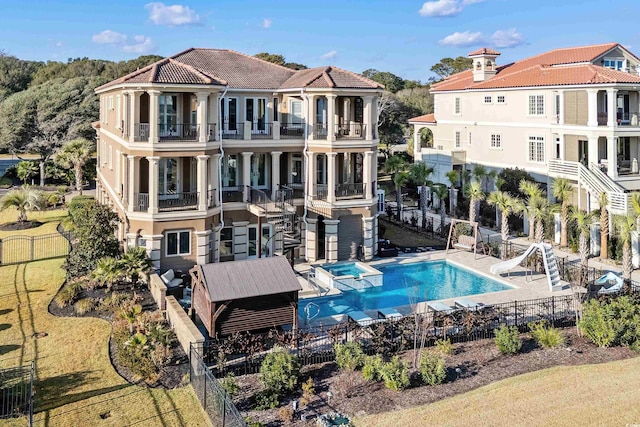 back of house featuring a balcony and a fenced in pool