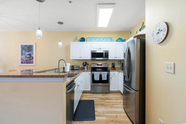 kitchen featuring appliances with stainless steel finishes, decorative light fixtures, sink, white cabinets, and kitchen peninsula