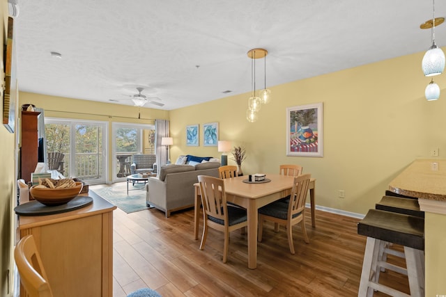 dining space with a textured ceiling, hardwood / wood-style flooring, and ceiling fan