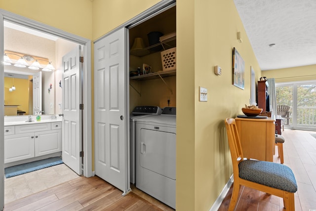 washroom featuring separate washer and dryer, light hardwood / wood-style floors, a textured ceiling, and sink