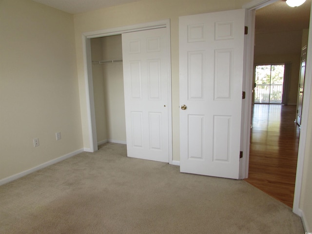 unfurnished bedroom featuring a closet and light colored carpet