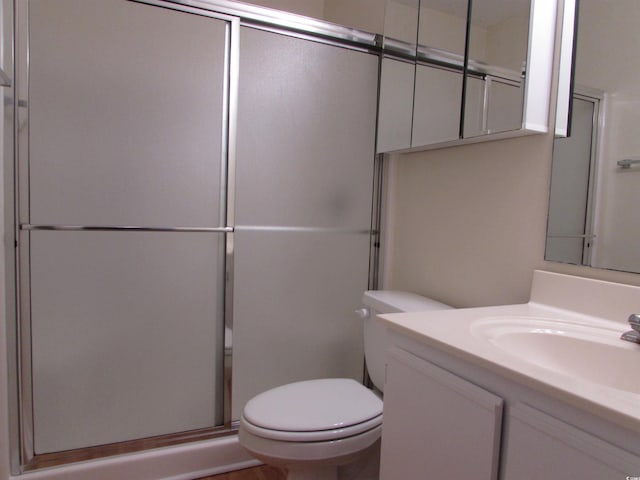 bathroom with vanity, a shower with shower door, and toilet