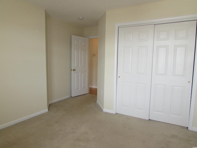 unfurnished bedroom with a closet and light carpet