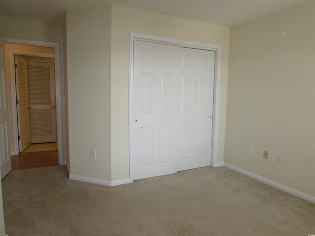 unfurnished bedroom with a closet and light carpet