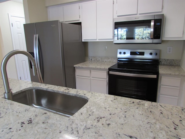 kitchen featuring light stone countertops, appliances with stainless steel finishes, sink, and white cabinets