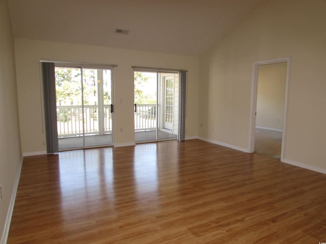 empty room featuring high vaulted ceiling and light wood-type flooring