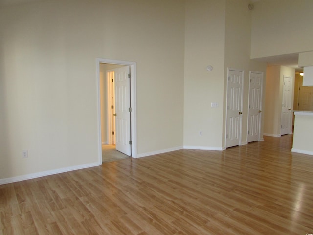 unfurnished room featuring a high ceiling and light hardwood / wood-style floors