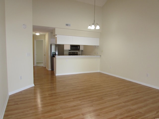 interior space featuring light hardwood / wood-style floors, high vaulted ceiling, and a chandelier