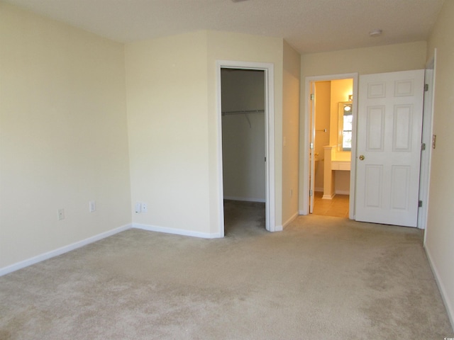 unfurnished bedroom featuring a spacious closet, connected bathroom, light carpet, and a closet