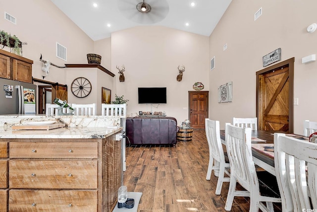 kitchen with ceiling fan, a barn door, wood-type flooring, and high vaulted ceiling