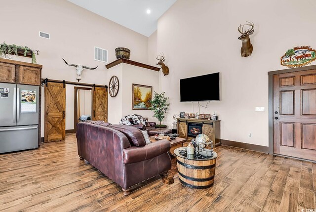 7299 Cartrette Rd, Aynor, SC 29511 - living room with high vaulted ceiling, light wood-style flooring, baseboards, a barn door, and recessed lighting