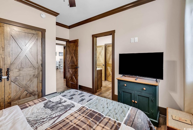 bedroom with a barn door, light hardwood / wood-style floors, ceiling fan, connected bathroom, and crown molding