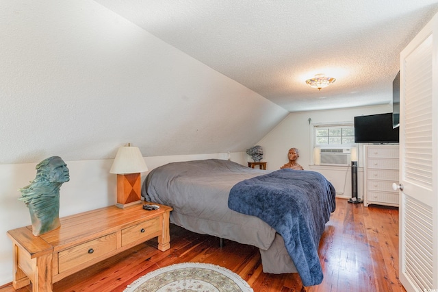 bedroom with dark wood-type flooring, a textured ceiling, cooling unit, and lofted ceiling