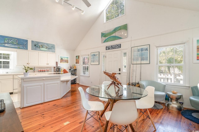 dining area with ceiling fan, light wood-type flooring, and high vaulted ceiling