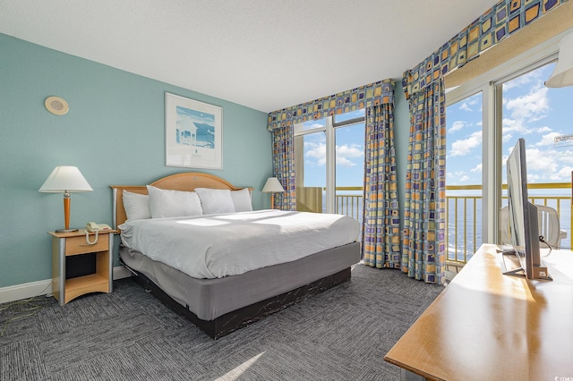 bedroom featuring multiple windows, dark carpet, and access to exterior