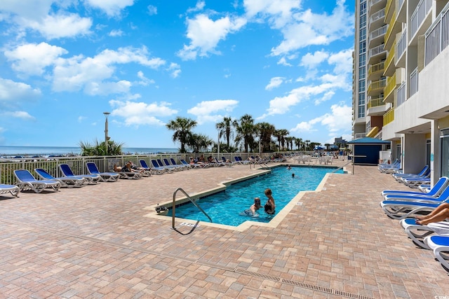 view of pool featuring a water view and a patio area