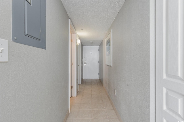 corridor with electric panel, a textured ceiling, and light tile patterned floors