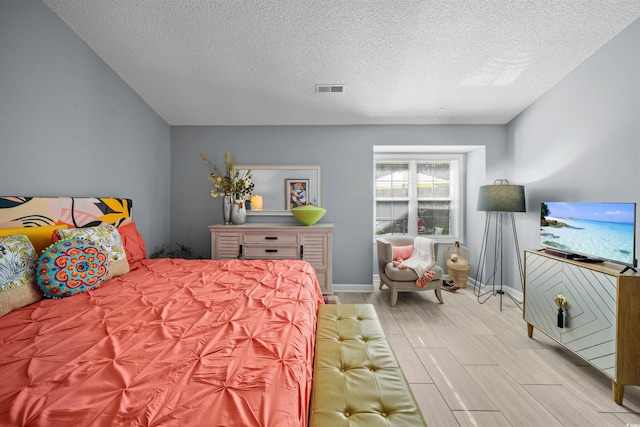 bedroom featuring wood tiled floor, a textured ceiling, visible vents, and baseboards