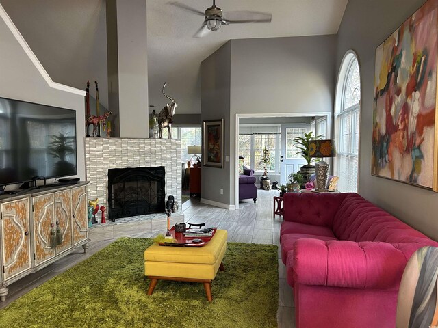 living room featuring ceiling fan with notable chandelier, a textured ceiling, light hardwood / wood-style flooring, and high vaulted ceiling