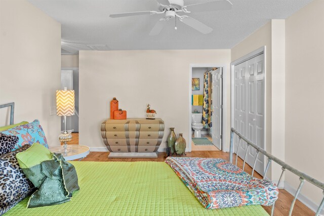 bedroom with a closet, ensuite bath, a textured ceiling, hardwood / wood-style floors, and ceiling fan