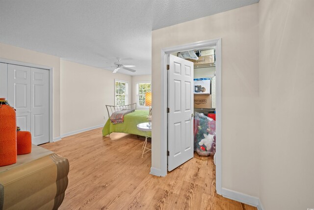 interior space featuring ceiling fan, a textured ceiling, and light hardwood / wood-style flooring