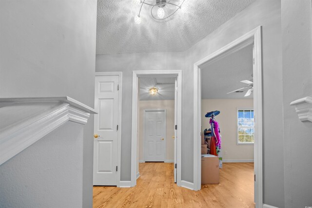 hall with light hardwood / wood-style flooring and a textured ceiling