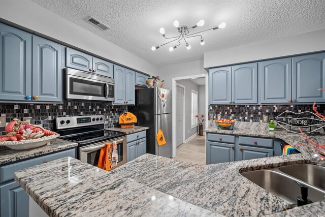 kitchen with light wood-type flooring, sink, backsplash, and appliances with stainless steel finishes