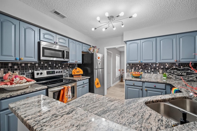 kitchen with light wood finished floors, visible vents, blue cabinets, stainless steel appliances, and a sink