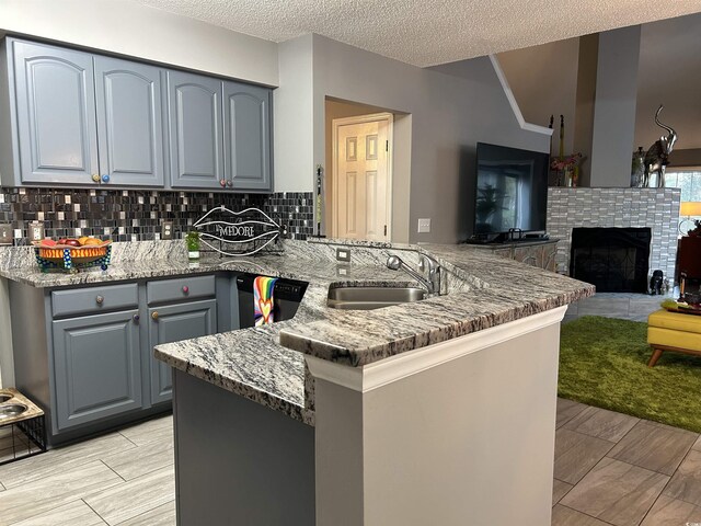 kitchen with kitchen peninsula, a textured ceiling, decorative light fixtures, and sink