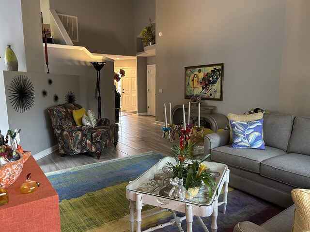 living room with ceiling fan, wood-type flooring, a stone fireplace, and high vaulted ceiling