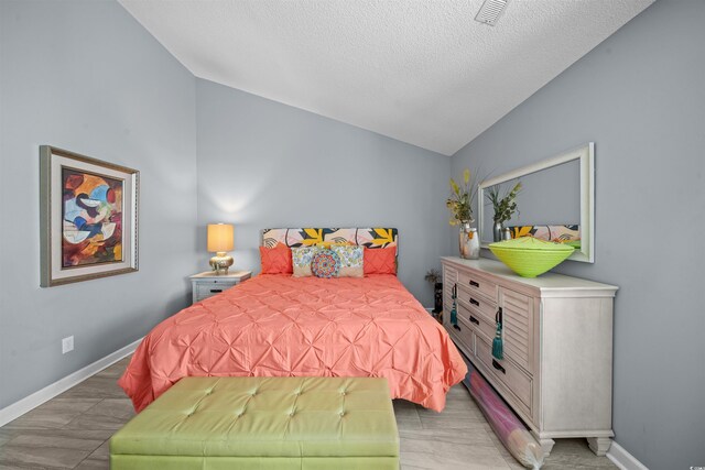 bedroom with hardwood / wood-style flooring, a textured ceiling, and vaulted ceiling