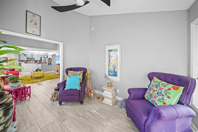 sitting room with ceiling fan and high vaulted ceiling