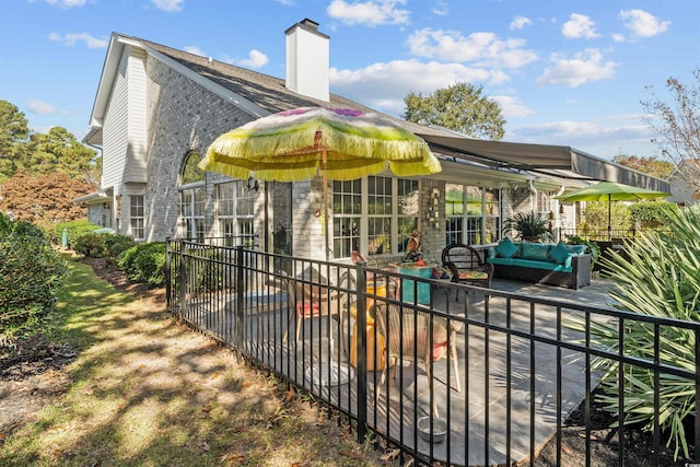 back of property with brick siding, a chimney, a patio area, and an outdoor living space