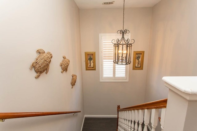 stairs featuring a notable chandelier and wood-type flooring