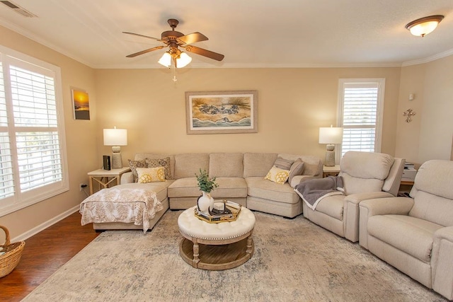 living room with dark wood-type flooring, a healthy amount of sunlight, crown molding, and ceiling fan