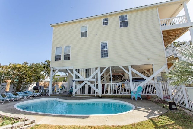 rear view of house featuring a fenced in pool and a patio